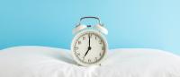 alarm clock perched on top of a white pillow